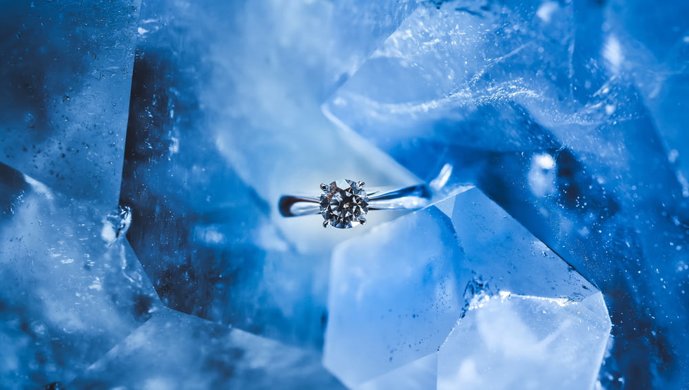 silver-colored ring with clear gemstone inside ice