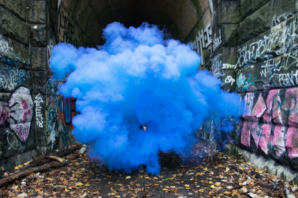 foto de fumaça azul ao lado de muros com grafite