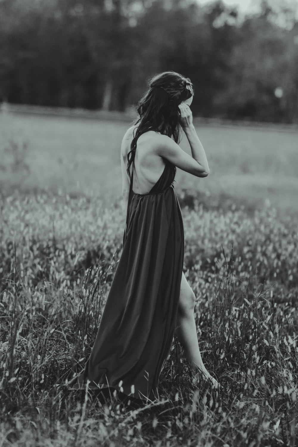 fotografia em tons de cinza da mulher usando o vestido no campo da grama enquanto está em pé