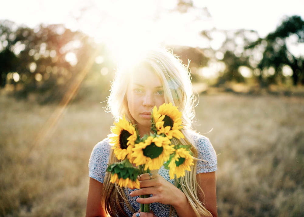 portrait photography of woman holding bouquet of sunflowers