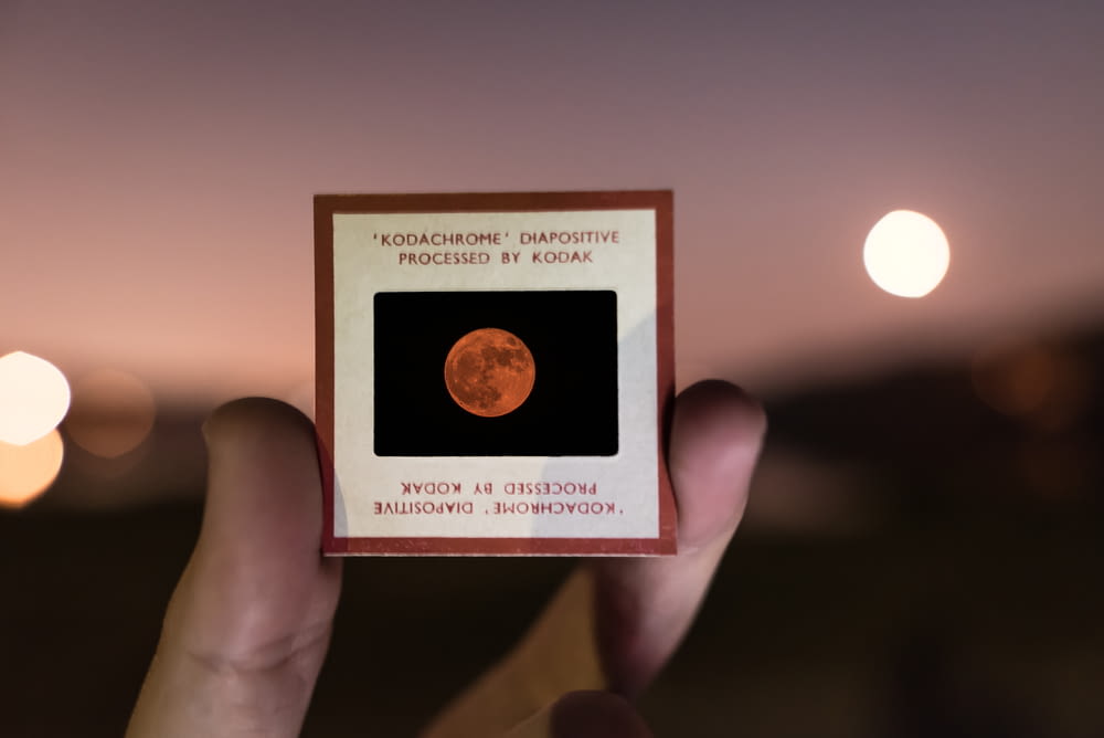 a person holding up a card with a picture of the moon