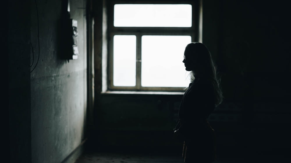 silhouette of woman standing while facing wall inside room