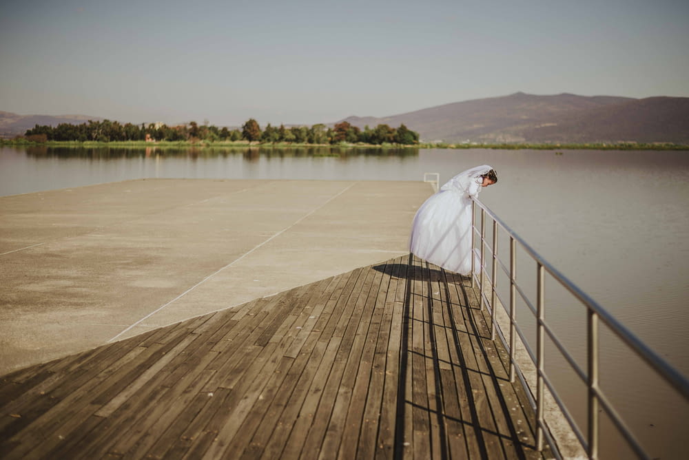woman wearing wedding dress looking on body of water