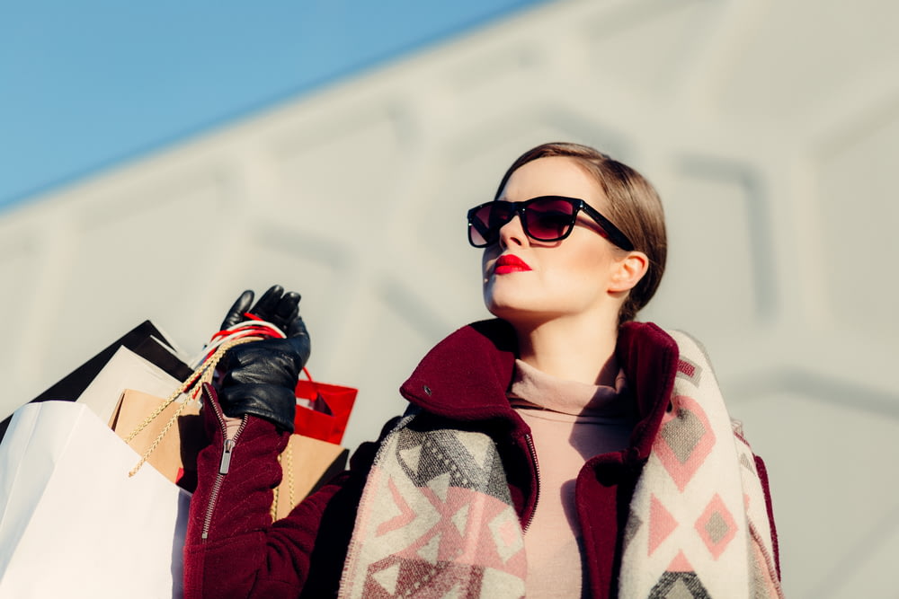 Flachfokusfotografie einer Frau, die tagsüber Einkaufstüten hält