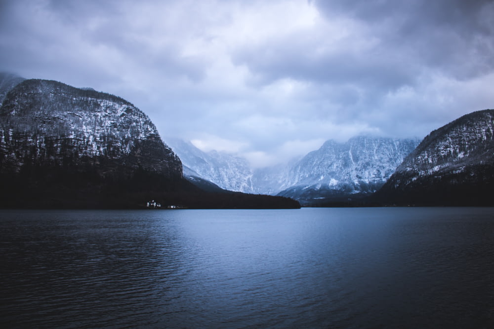 landscape photography of mountains near body of water under cloudy sky