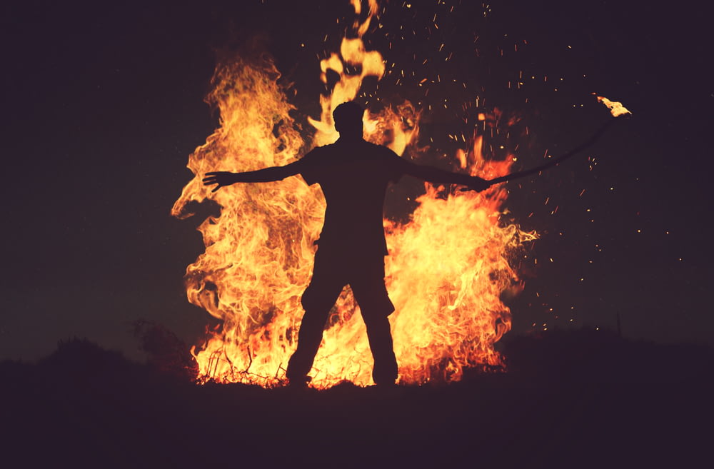 pessoa em pé na frente do fogo durante a noite
