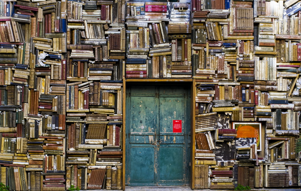 Porte en bois bleu entourée d’un mur recouvert de livres