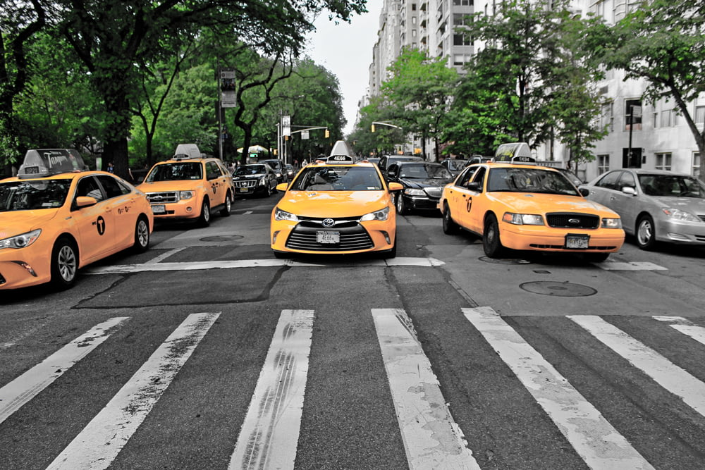 Cuatro coches amarillos en una carretera gris
