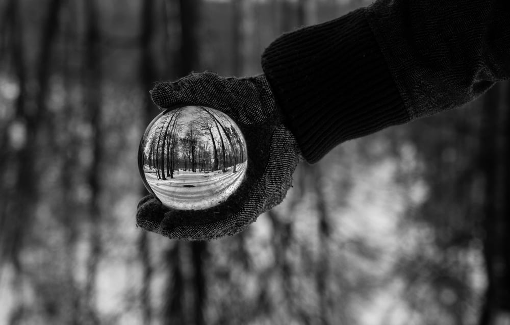 pessoa segurando a bola de cristal clara fotografia em tons de cinza