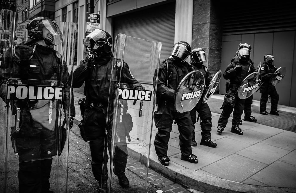 Polizisten halten durchsichtiges Fiberglasschild in der Hand