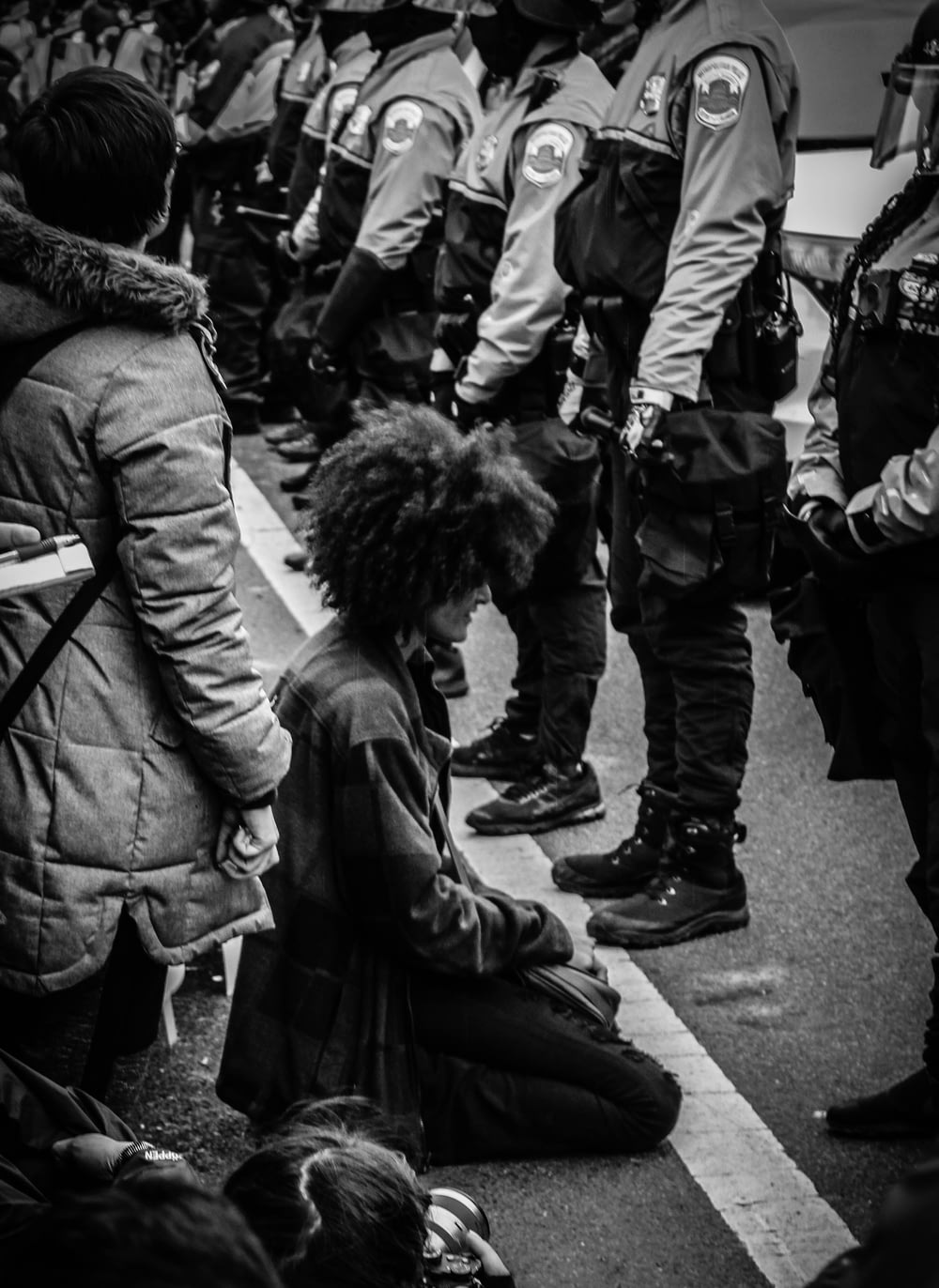 Person kniet vor Polizeibeamten