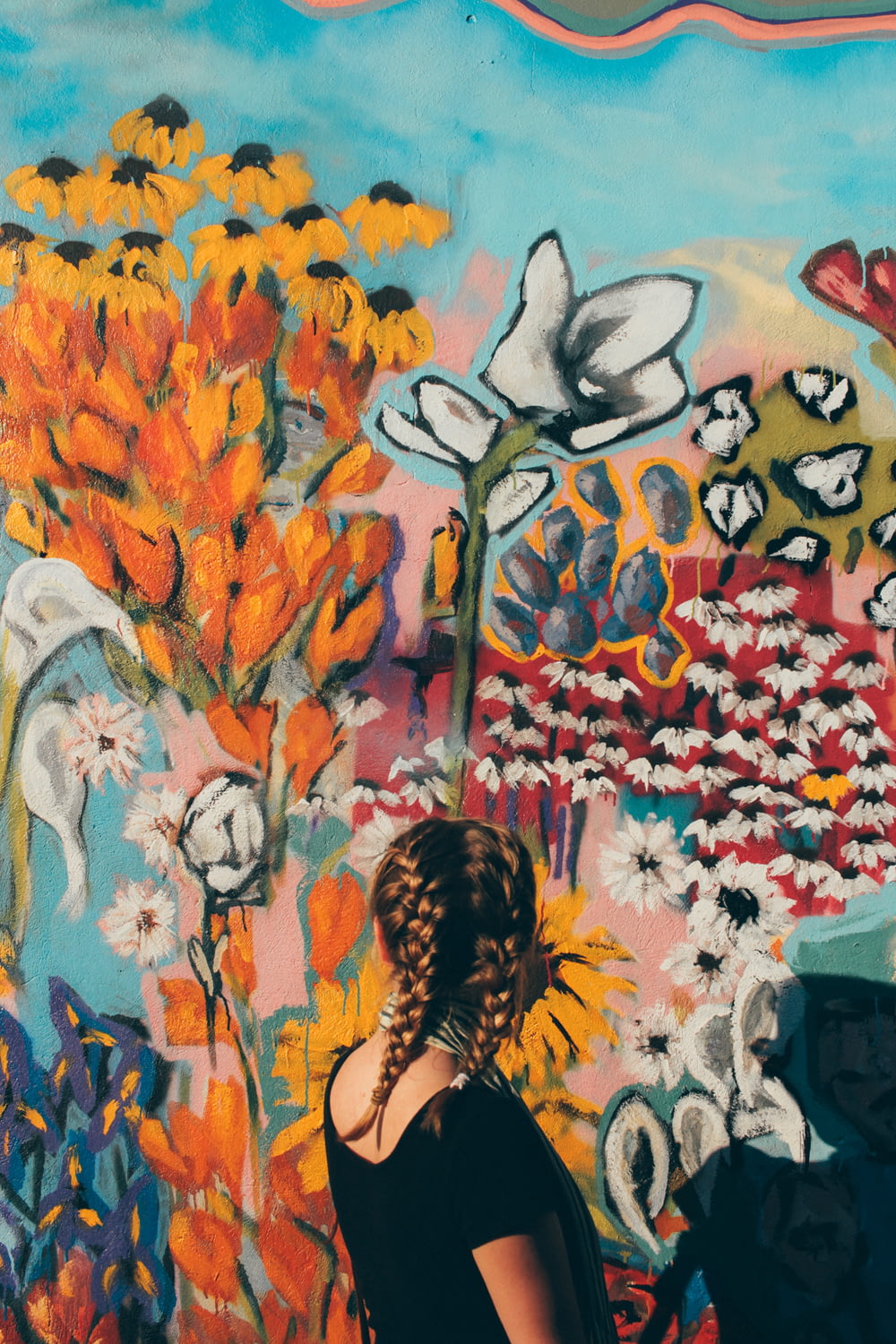 mujer mirando frente a la pared de graffiti floral