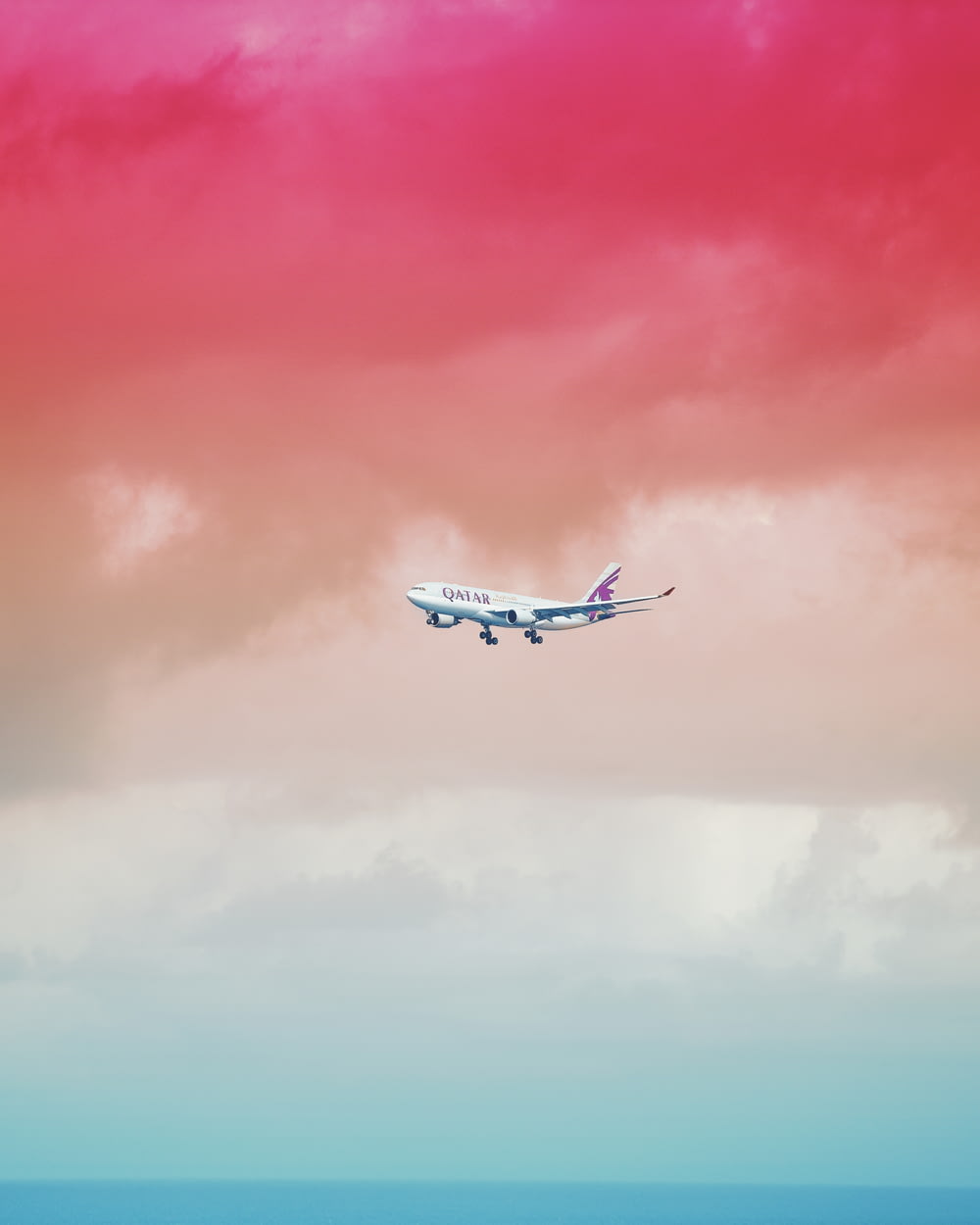 Qatar Airlines airplane flying under red cloud formation