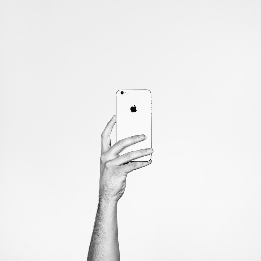 A person holding up an Apple phone.