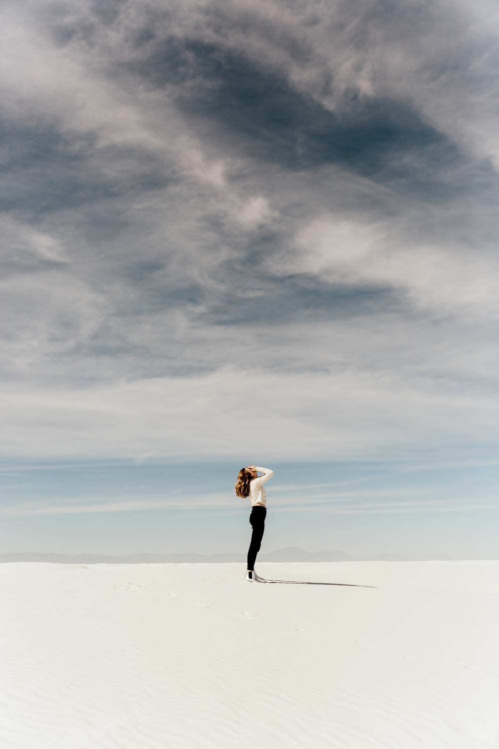 donna che guarda il cielo mentre si trova sulla sabbia bianca