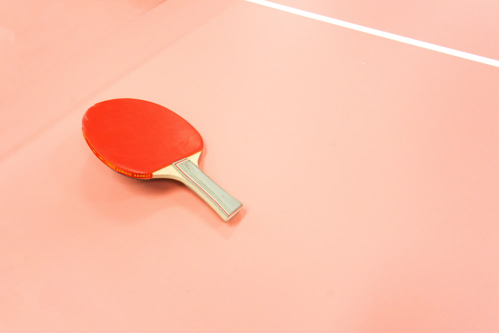 Une pagaie de tennis de table rouge assise sur un court.