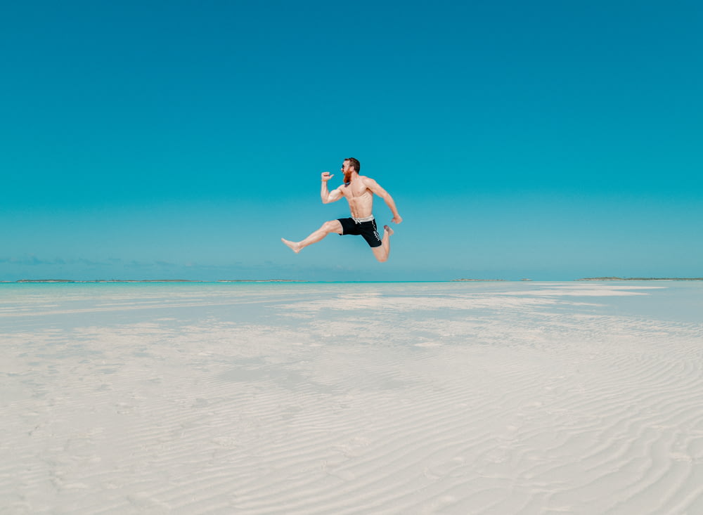 Photographie en accéléré d’un homme sautant au bord de la mer