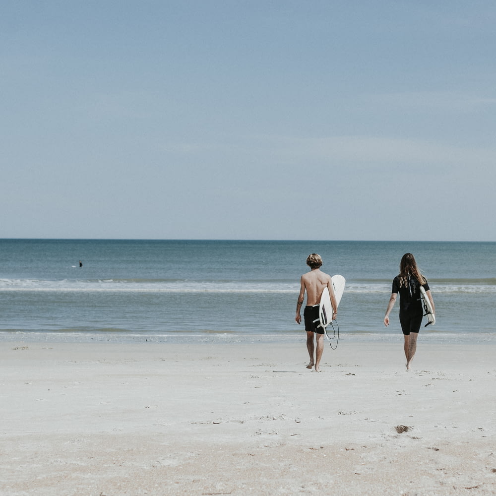 two person walking on coast