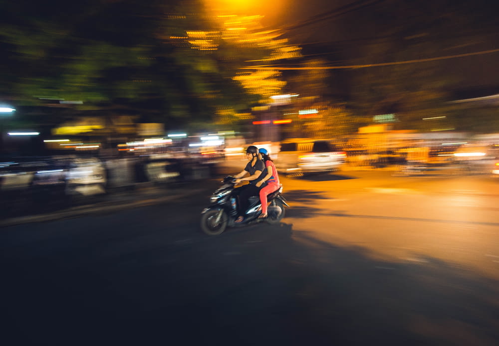couple roulant sur un scooter noir pendant la nuit
