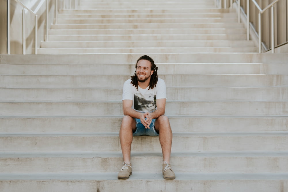 homme souriant assis sur l’escalier