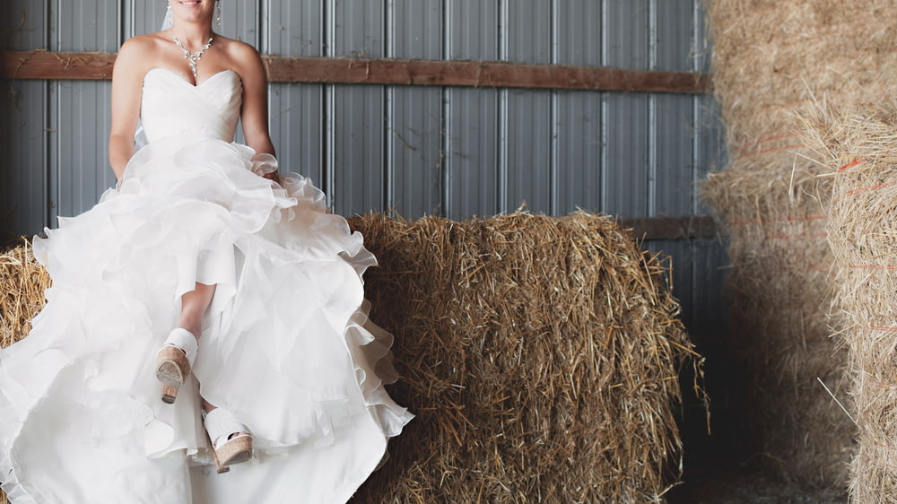 woman in ruffled wedding gown sitting on haystack
