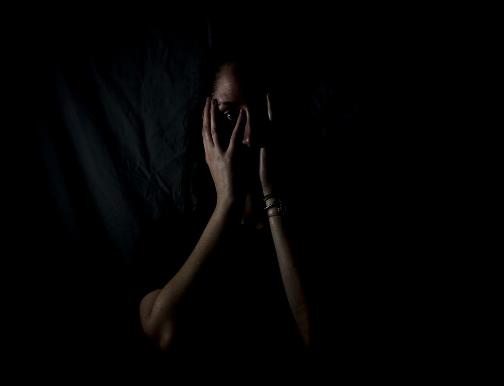 mujer sosteniendo su rostro en cuarto oscuro
