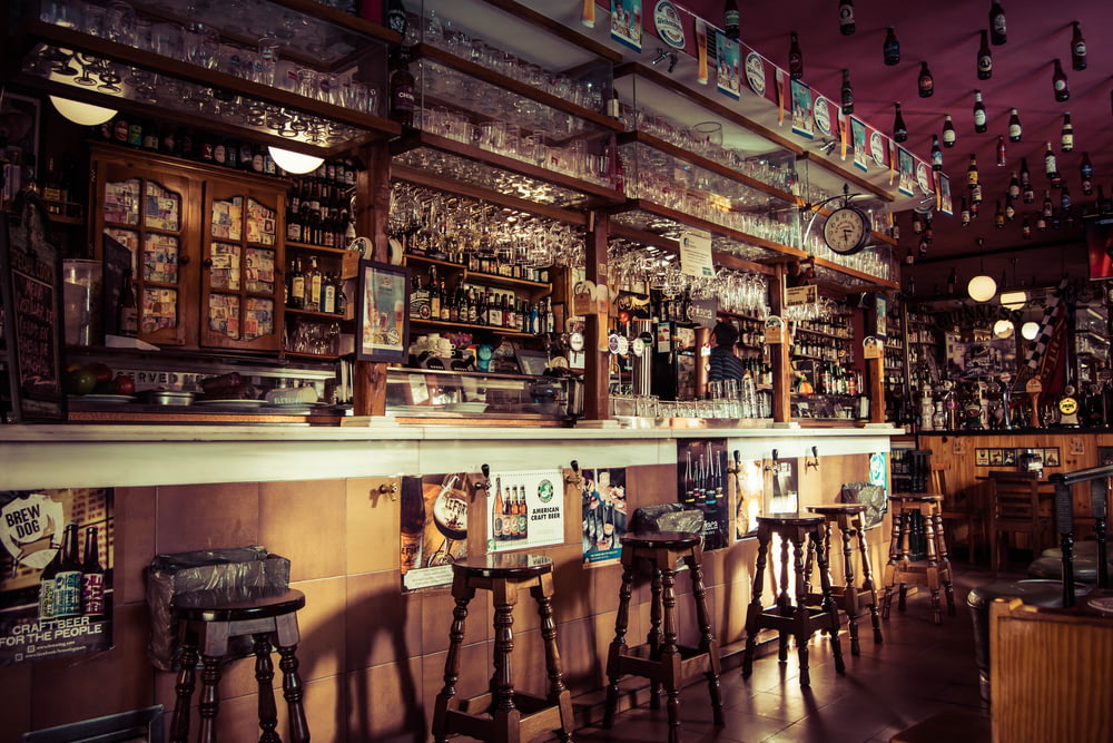 The interior of a bar with stools, glass cups and empty bottles attached to the roof in Madrid