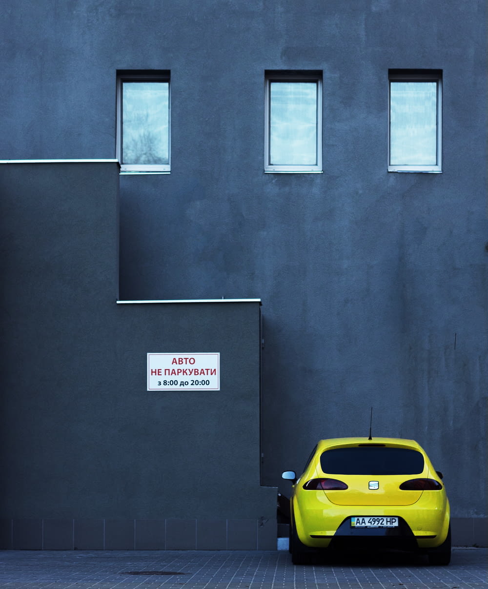 yellow SEAT car parking near concrete building
