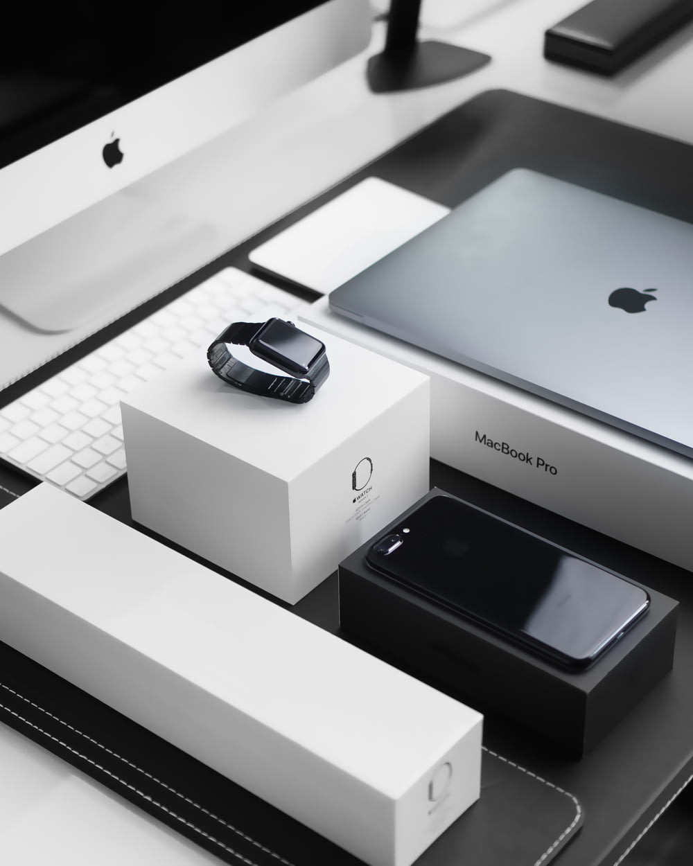 Capa preta Apple Watch, MacBook Pro prateado, iPhone 7 Plus preto a jato e iMac prateado com caixas correspondentes