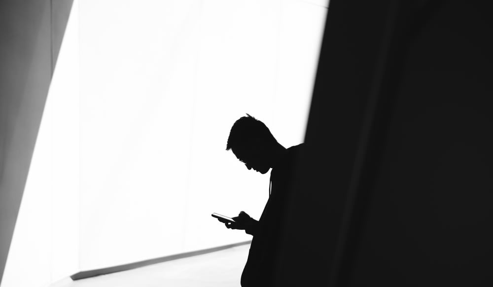 Persona che usa il telefono appoggiato al muro nella fotografia della silhouette