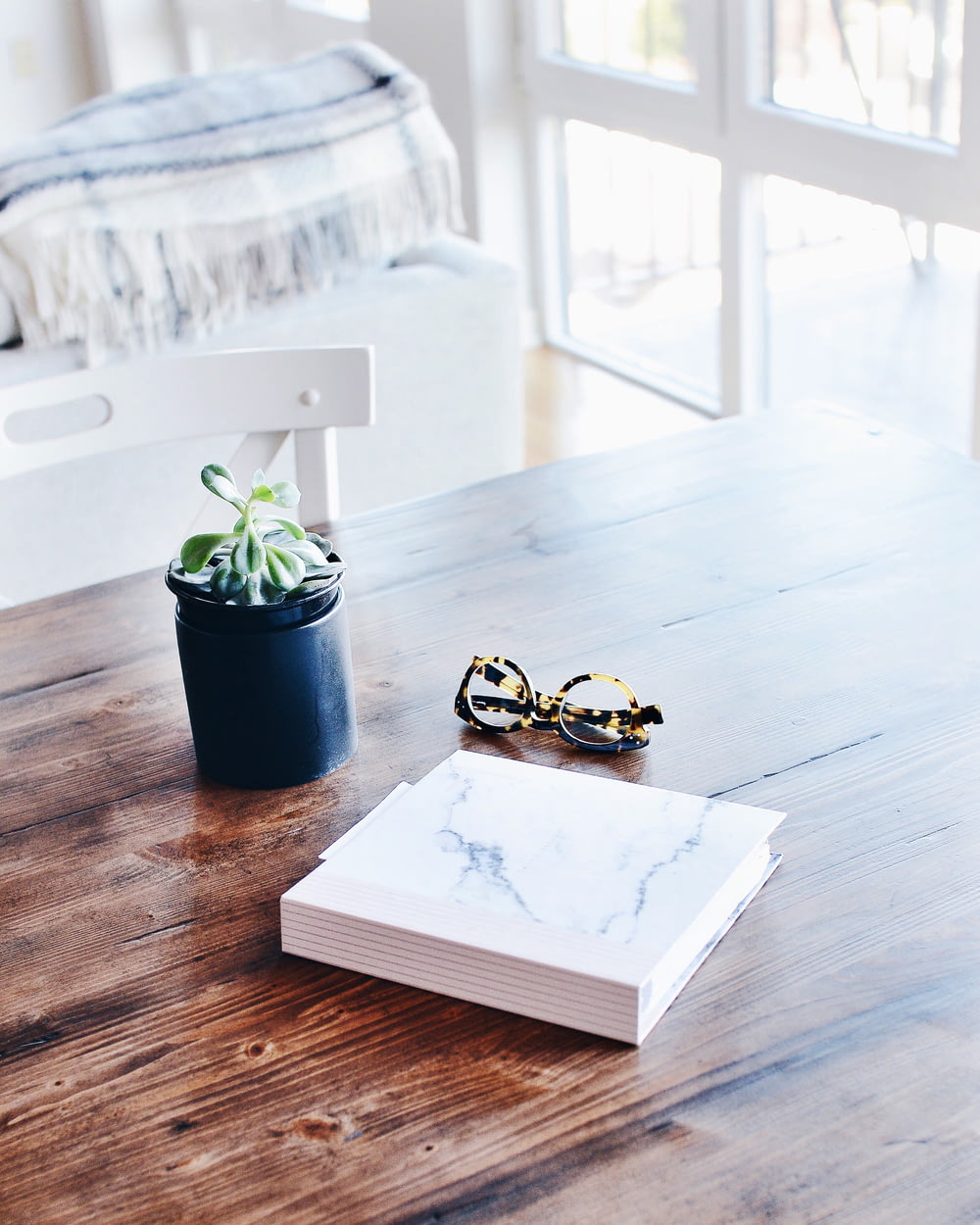 Livre relié à côté de lunettes et d’une plante succulente sur la table à l’intérieur de la pièce