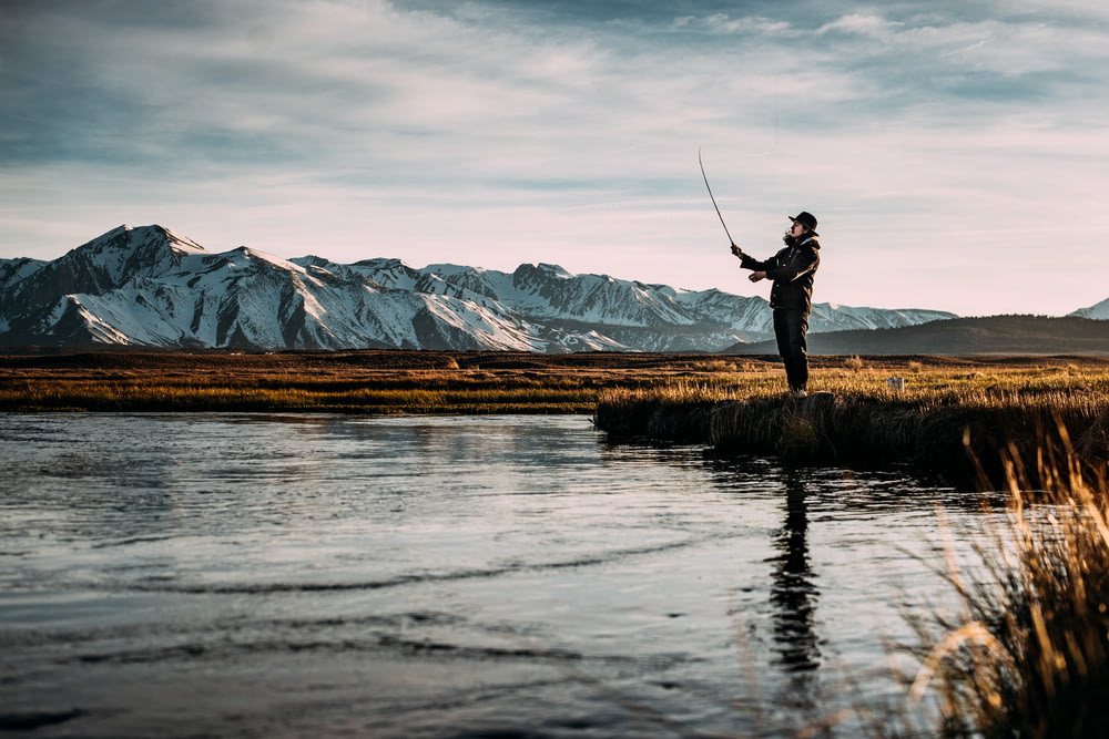 Photo de paysage d’un homme pêchant sur une rivière près des Alpes de montagne