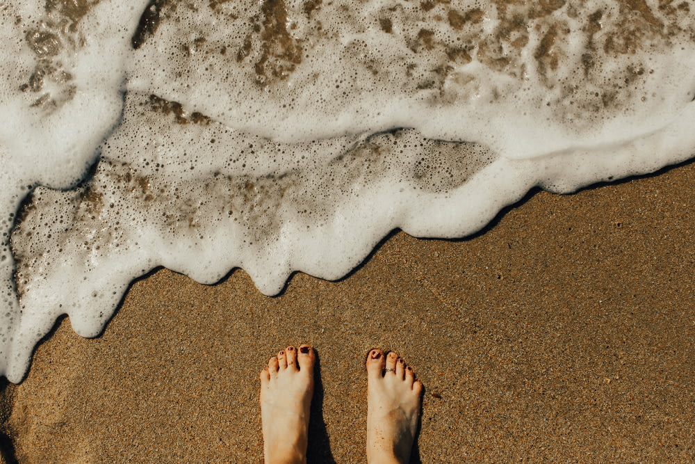 person's feet on seashore
