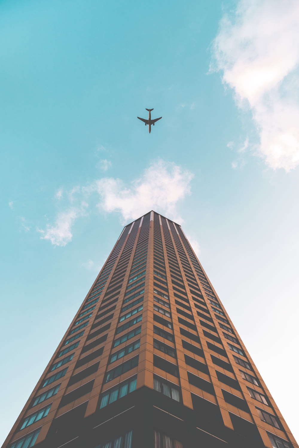 Foto da vista inferior do avião voando acima do edifício do arranha-céu