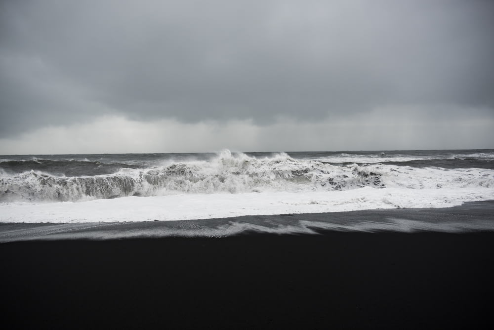 foto in scala di grigi della riva sotto le nuvole