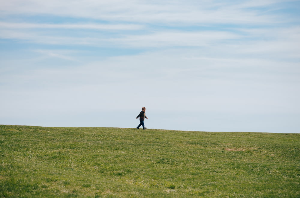 niño caminando en el campo de hierba verde