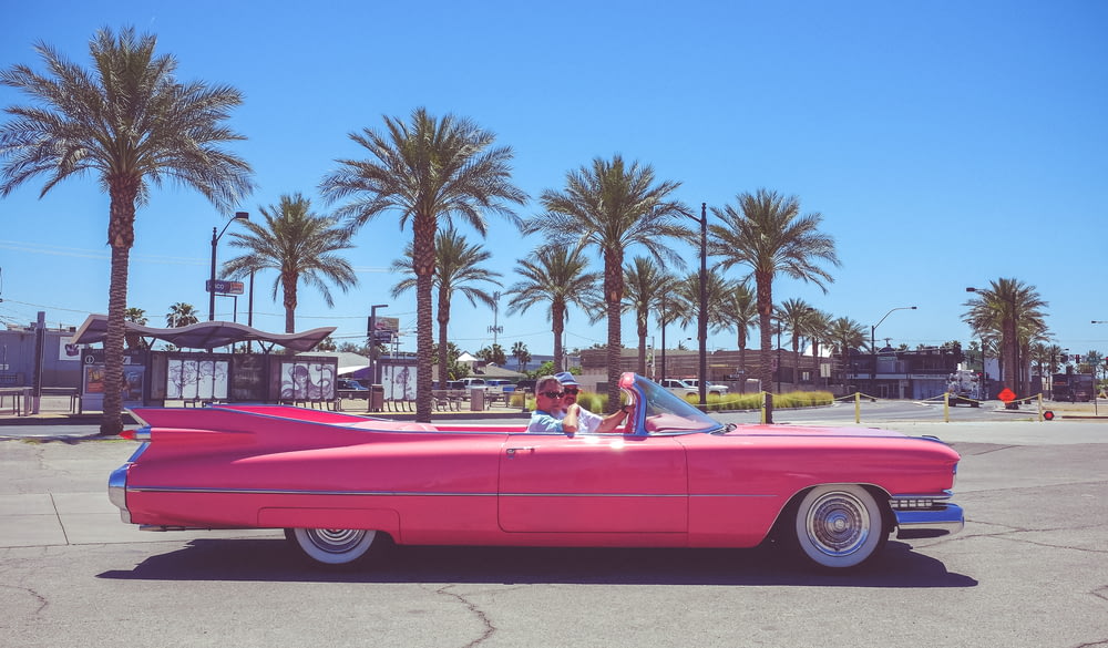 people in pink convertible coupe