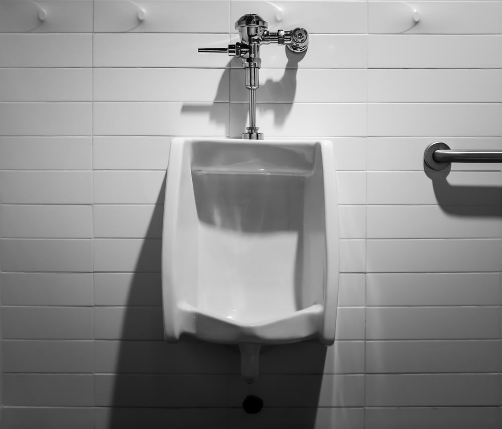 a urinal mounted to a wall in a bathroom
