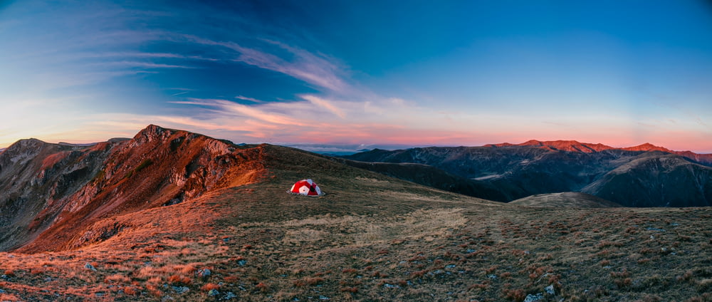 red and white camping tent on top of the mountain during daytime