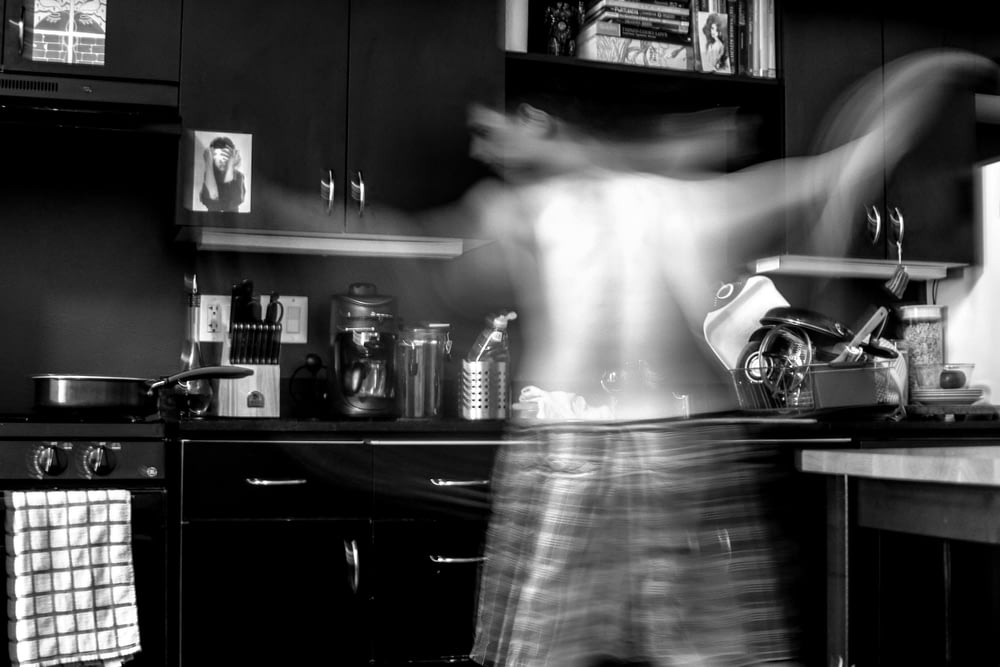 Hombre moviéndose en la cocina en fotografía en escala de grises