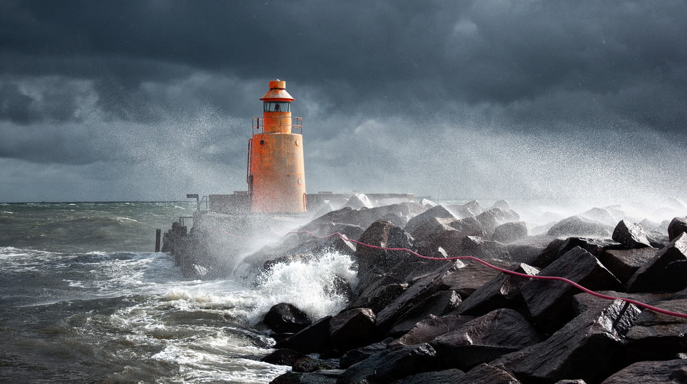 orange lighthouse on rock