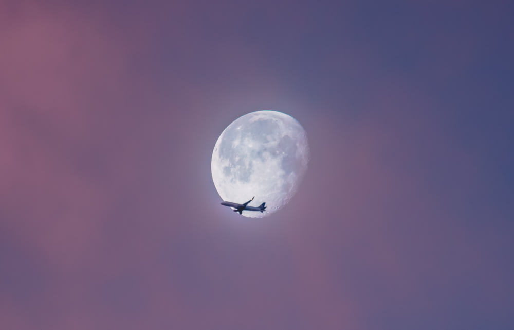 flying plane at sky during full moon at daytime