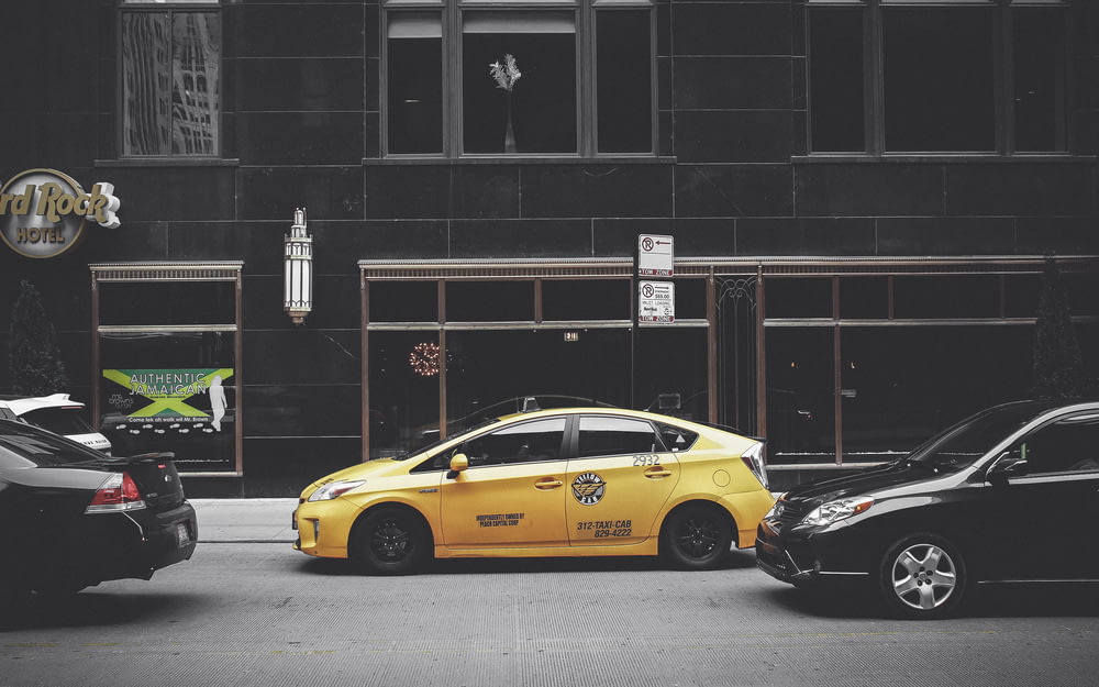 yellow sedan in front of brown building
