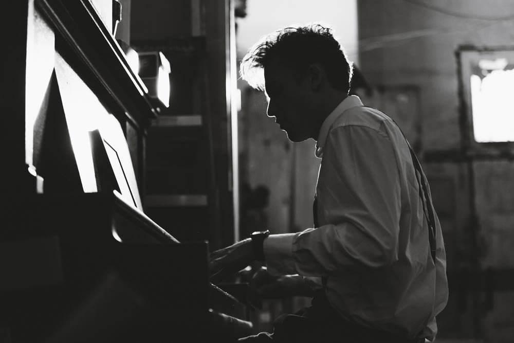 grayscale photography man playing piano