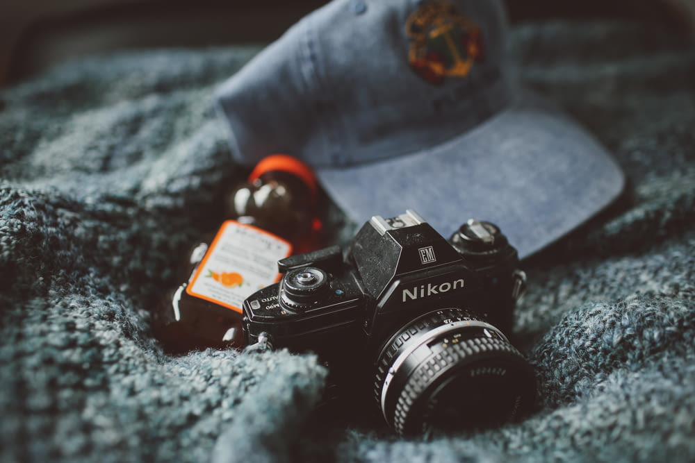 Nikon-Kamera in der Nähe von Honigflasche und blauer Kappe auf grauem Textil