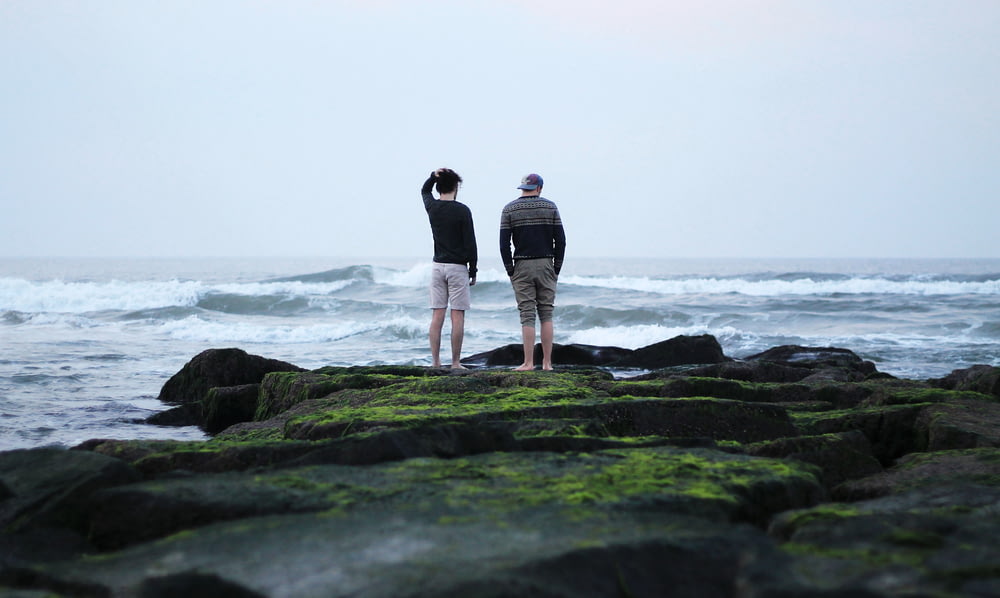 zwei Männer, die auf einer Klippe über dem Meer stehen