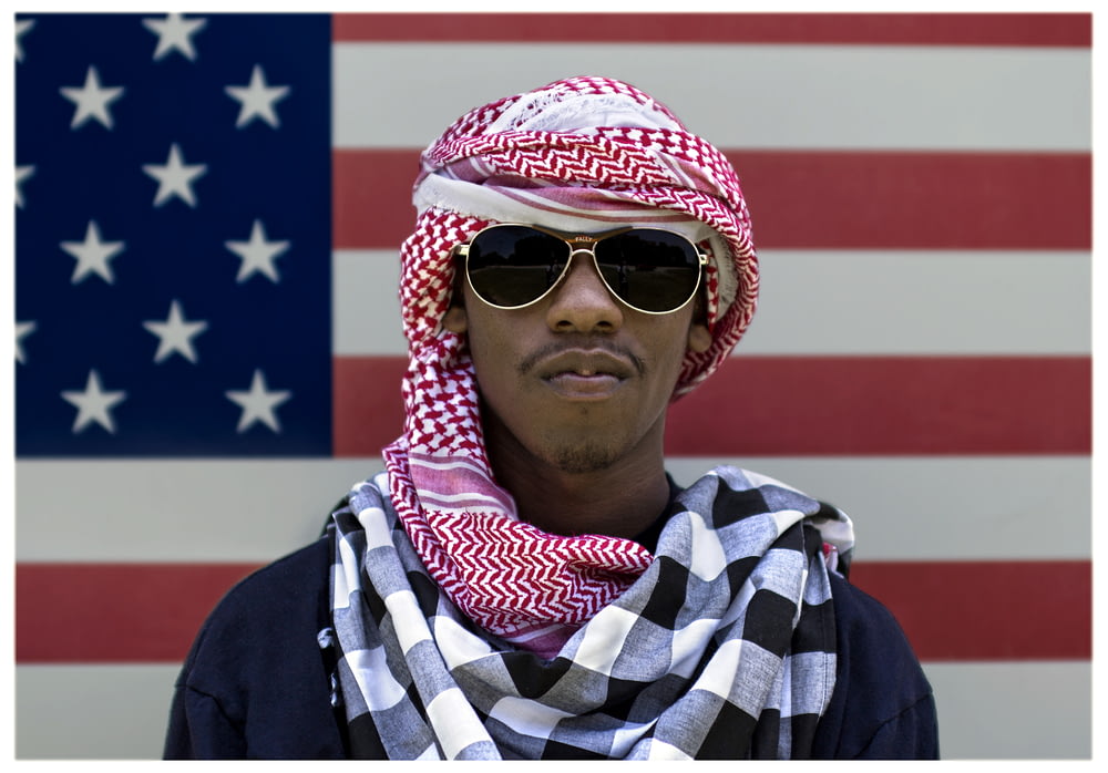 man wearing sunglasses in front of American flag