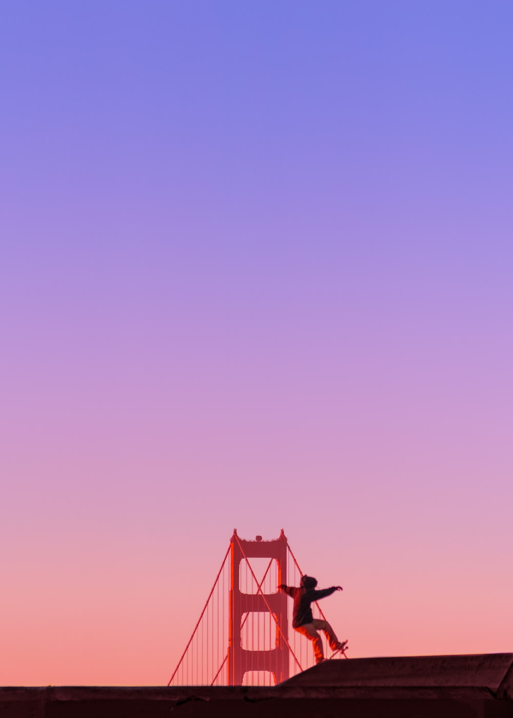 uomo che cavalca sullo skateboard davanti al Golden Gate Bridge