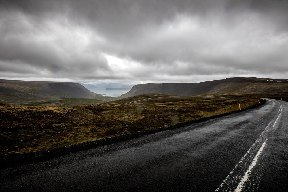 昼間の曇り空の下、山の近くの灰色のアスファルト道路