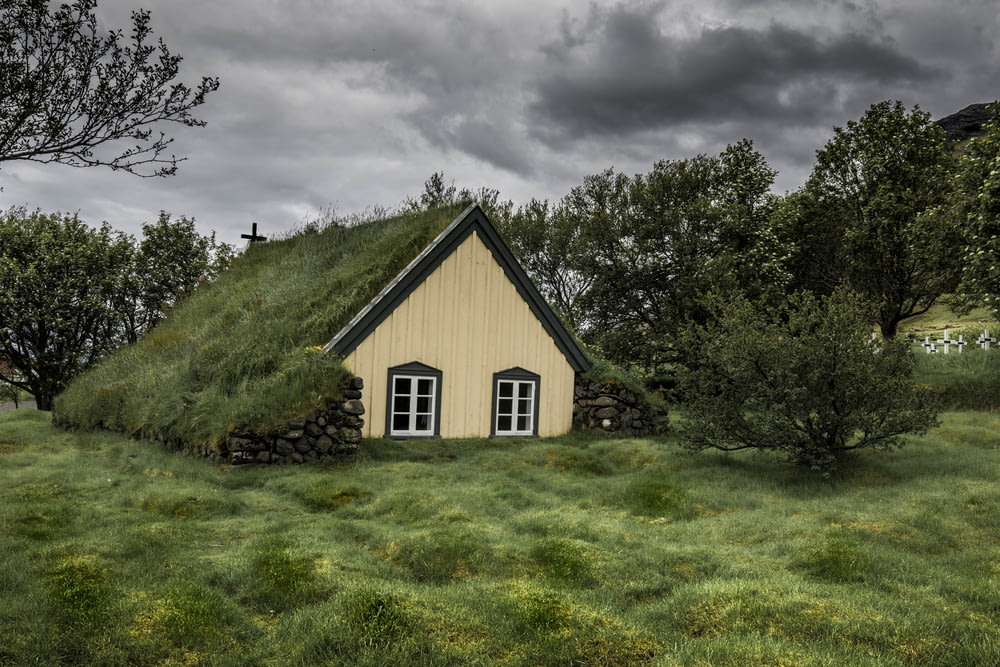 casa de madeira marrom cercada com árvores verdes sob nuvens cinzentas